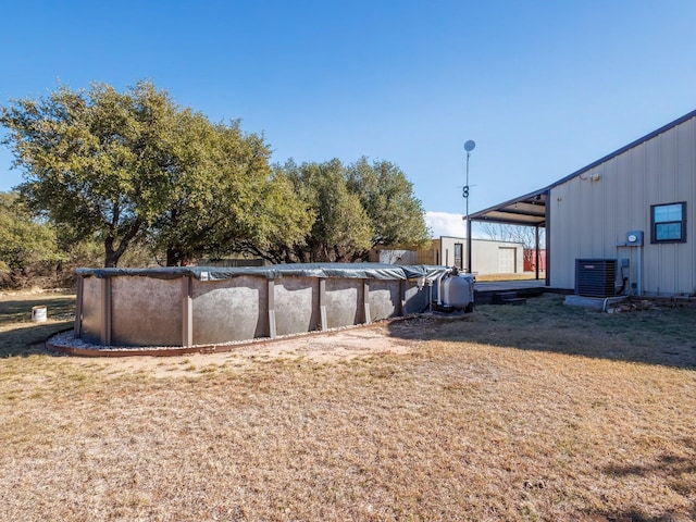 view of yard with central AC unit and a covered pool