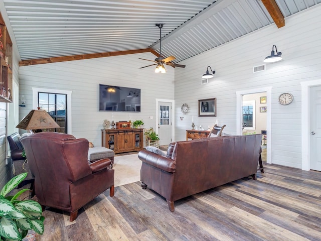 living room with hardwood / wood-style floors, lofted ceiling with beams, ceiling fan, and wood walls