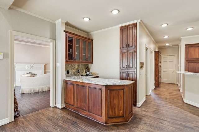 kitchen featuring dark hardwood / wood-style flooring, crown molding, kitchen peninsula, and tasteful backsplash