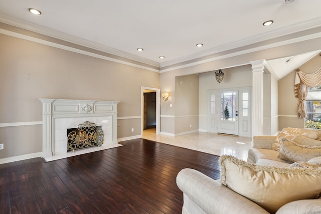 living room featuring ornate columns, ornamental molding, hardwood / wood-style floors, and a tile fireplace