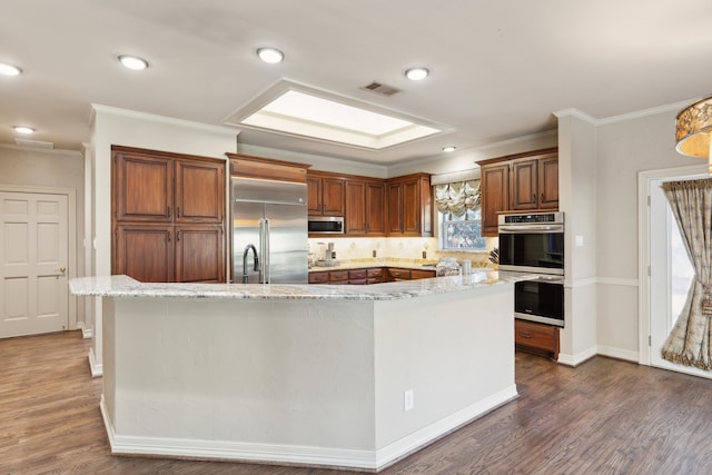 kitchen with appliances with stainless steel finishes, crown molding, dark hardwood / wood-style floors, and a center island