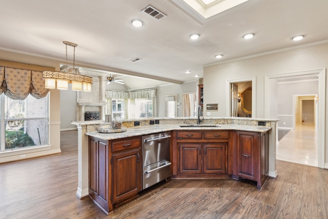 kitchen with hanging light fixtures, ceiling fan, sink, and a large island