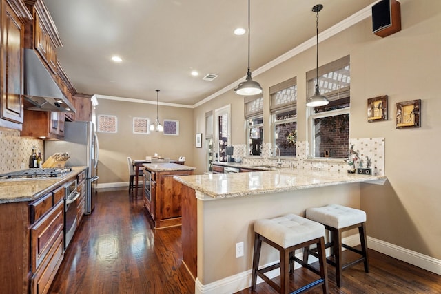 kitchen with kitchen peninsula, light stone countertops, tasteful backsplash, exhaust hood, and pendant lighting