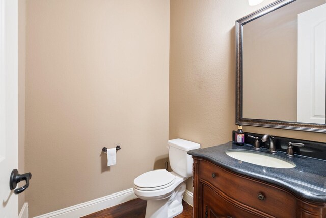 bathroom with hardwood / wood-style floors, vanity, and toilet