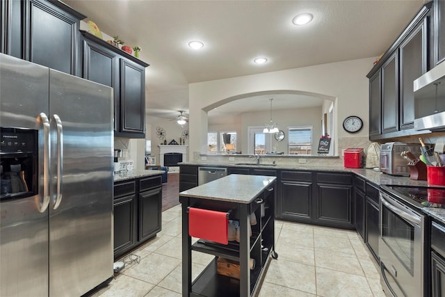 kitchen with decorative light fixtures, sink, decorative backsplash, kitchen peninsula, and stainless steel appliances