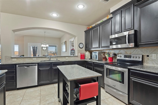 kitchen featuring light tile patterned flooring, sink, decorative light fixtures, appliances with stainless steel finishes, and backsplash