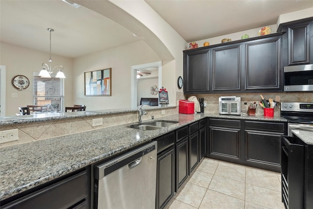 kitchen with sink, light tile patterned floors, stainless steel appliances, light stone counters, and tasteful backsplash