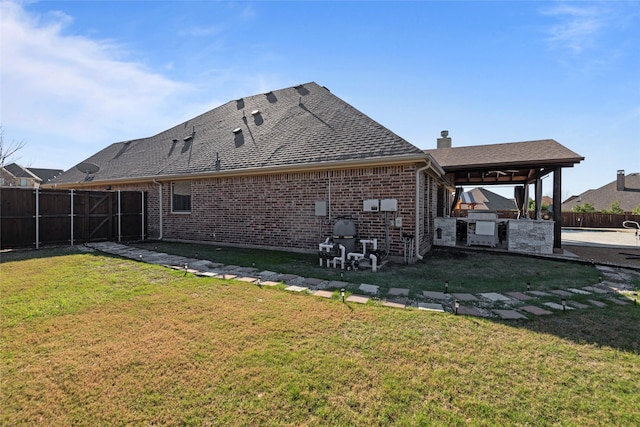 rear view of house featuring a lawn and an outdoor kitchen