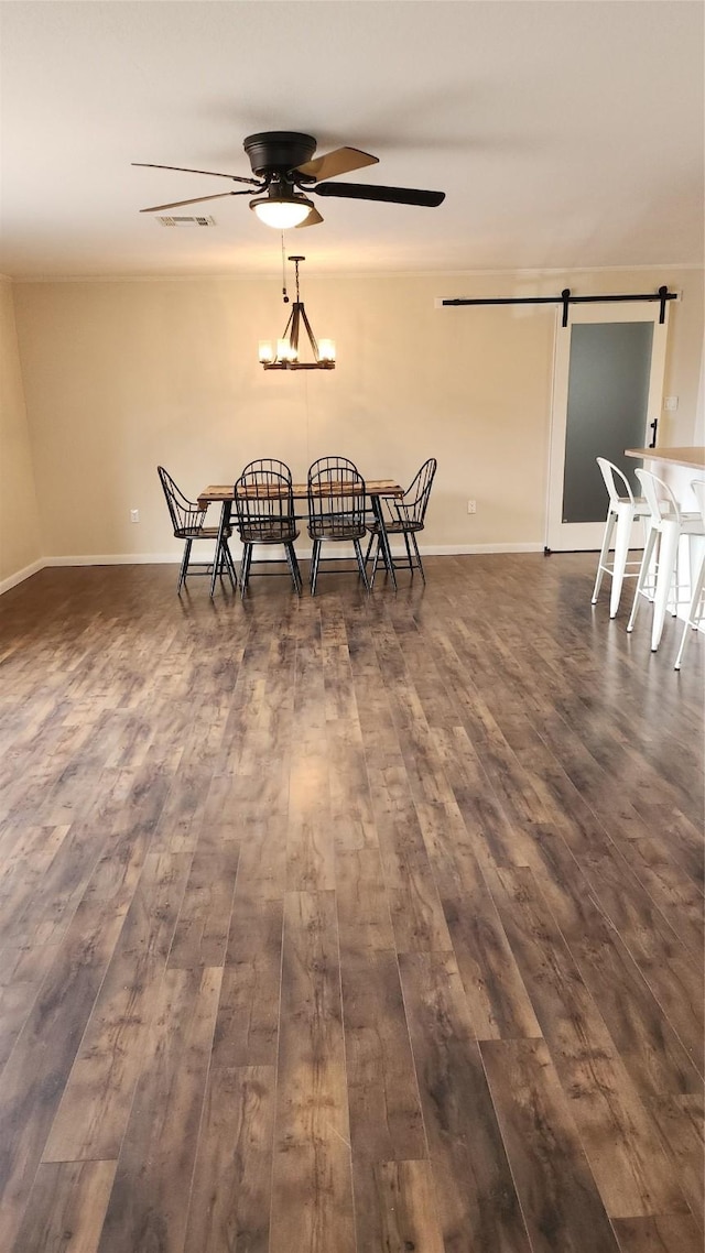 dining room with a barn door, dark wood-type flooring, and ceiling fan