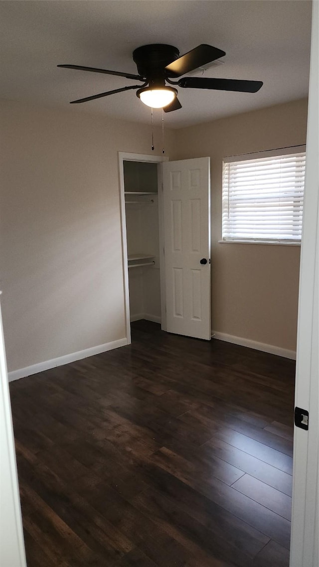 unfurnished bedroom featuring dark wood-type flooring, ceiling fan, and a closet