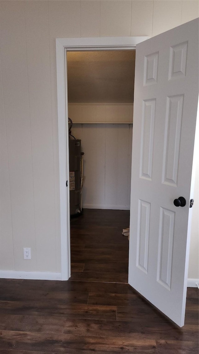 hallway featuring strapped water heater and dark hardwood / wood-style floors