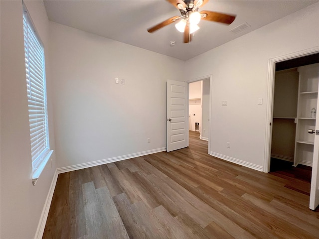 unfurnished bedroom featuring multiple windows, ceiling fan, a closet, and hardwood / wood-style flooring