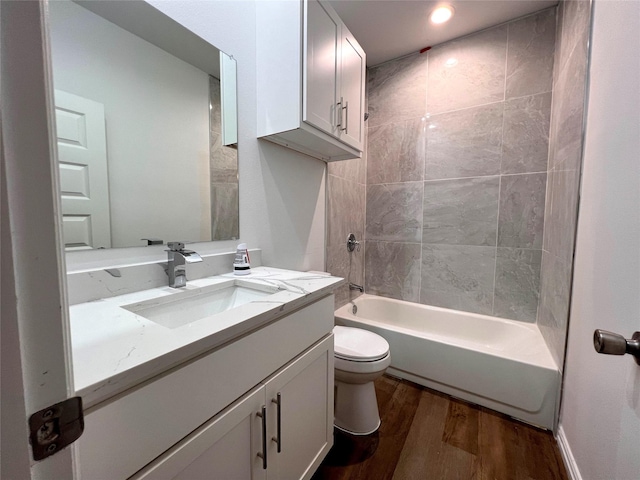 full bathroom featuring vanity, wood-type flooring, tiled shower / bath combo, and toilet