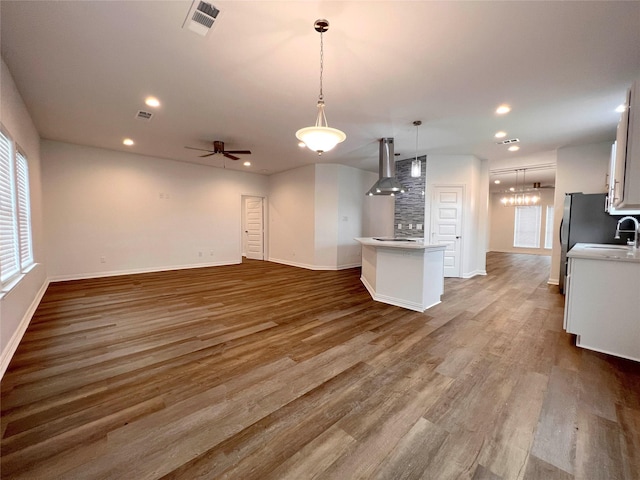 unfurnished living room featuring ceiling fan, sink, and hardwood / wood-style flooring