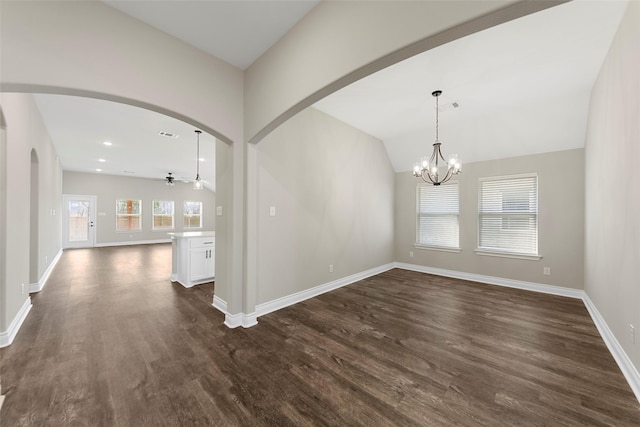 unfurnished room featuring ceiling fan with notable chandelier, dark hardwood / wood-style flooring, and vaulted ceiling