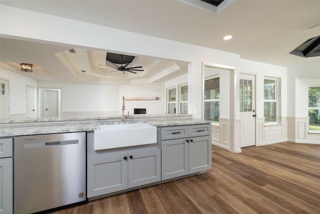 kitchen featuring sink, gray cabinets, light stone counters, a tray ceiling, and stainless steel dishwasher