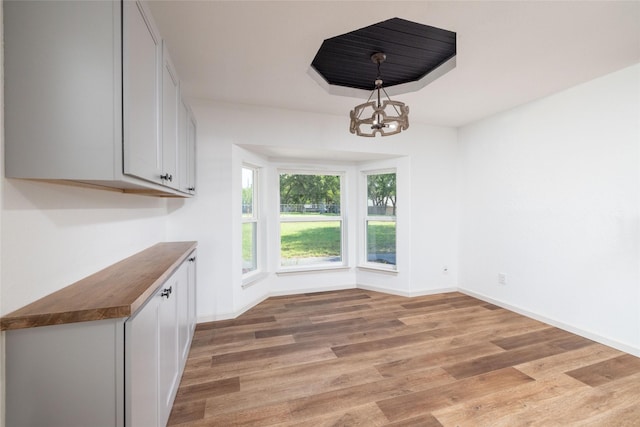 unfurnished dining area featuring an inviting chandelier and light hardwood / wood-style flooring