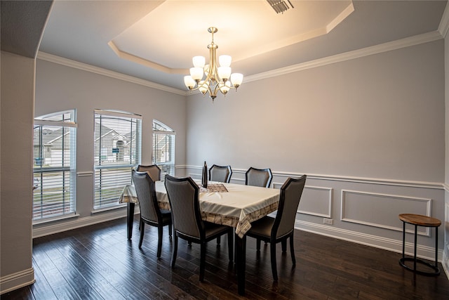 dining space with dark hardwood / wood-style floors, a raised ceiling, ornamental molding, and an inviting chandelier