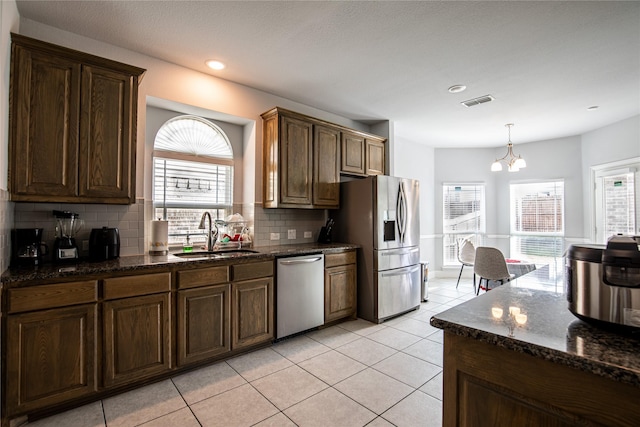 kitchen with sink, backsplash, a chandelier, light tile patterned floors, and appliances with stainless steel finishes