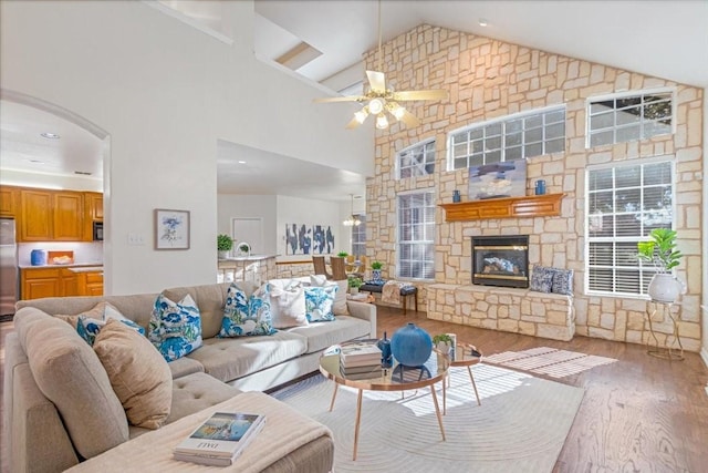 living room featuring high vaulted ceiling, a fireplace, wood finished floors, and a ceiling fan