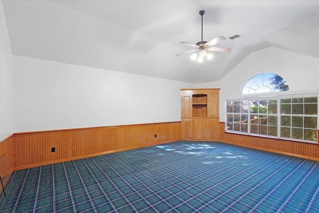 bonus room with dark carpet, ceiling fan, lofted ceiling, and wood walls