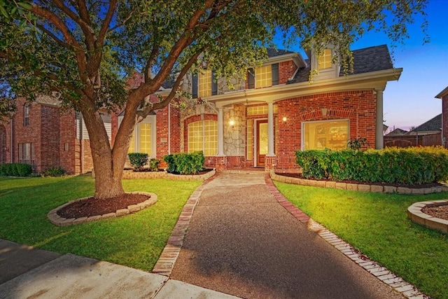 view of front facade featuring stone siding, brick siding, and a front lawn