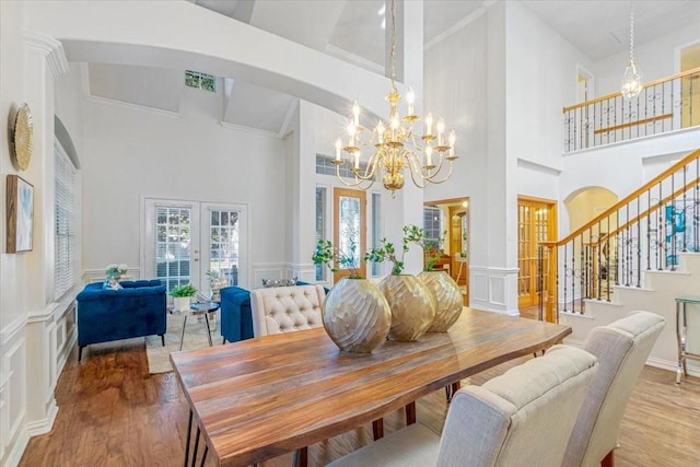 dining room featuring a chandelier, french doors, hardwood / wood-style flooring, and a high ceiling