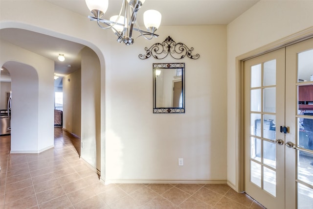 unfurnished dining area featuring light tile patterned floors, french doors, and a chandelier