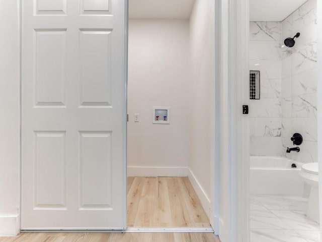 bathroom featuring hardwood / wood-style flooring, tiled shower / bath combo, and toilet