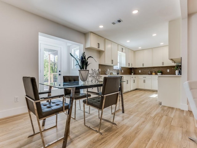 kitchen with white cabinets, tasteful backsplash, and light hardwood / wood-style flooring