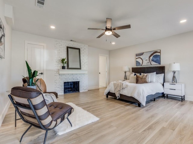 bedroom with ceiling fan, light hardwood / wood-style floors, and a brick fireplace