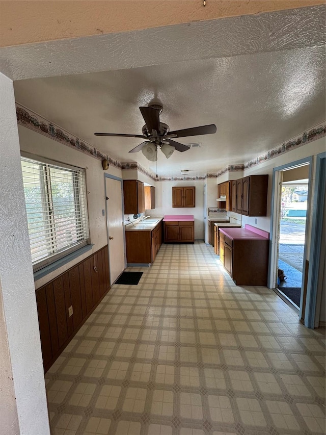 kitchen featuring ceiling fan, wood walls, and a textured ceiling