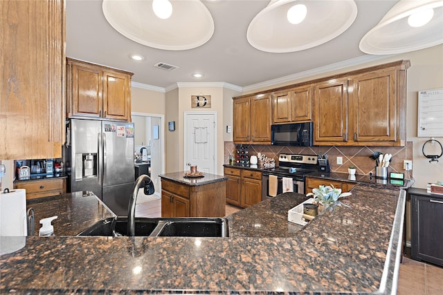 kitchen featuring sink, a center island, tasteful backsplash, dark stone counters, and appliances with stainless steel finishes