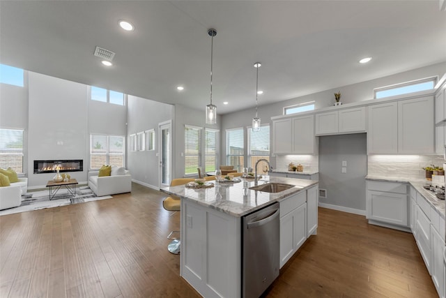 kitchen with sink, white cabinetry, stainless steel appliances, and a kitchen island with sink