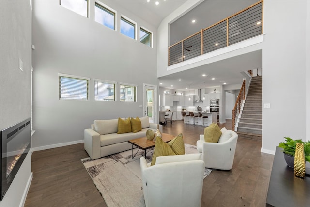 living room with heating unit, a towering ceiling, and dark hardwood / wood-style floors