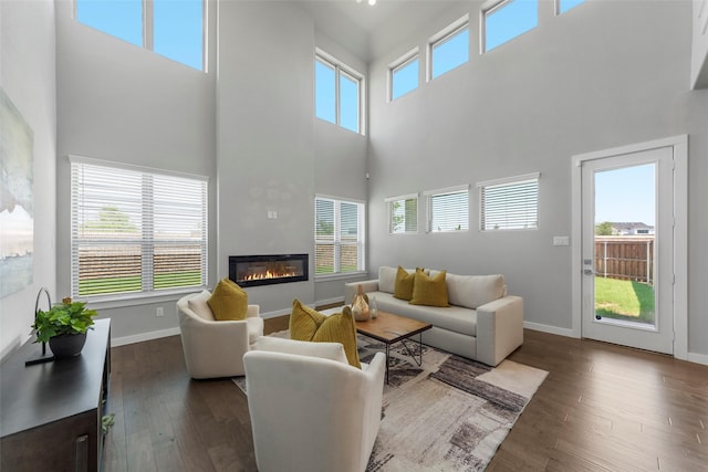 living room with a fireplace, a towering ceiling, and dark hardwood / wood-style floors