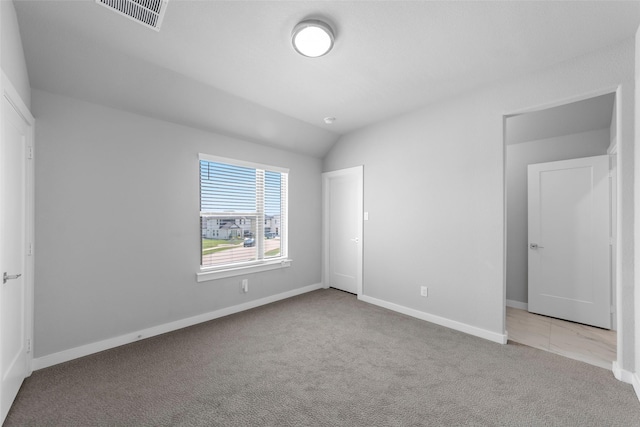 unfurnished bedroom with light colored carpet and vaulted ceiling