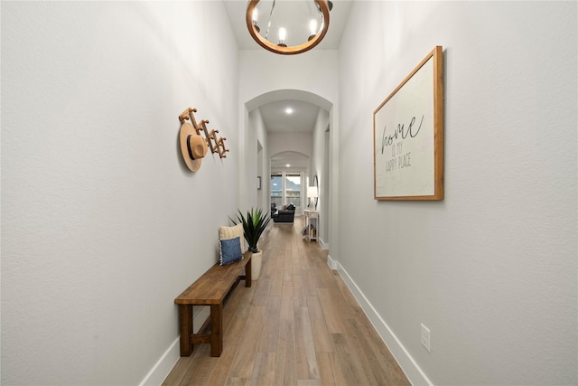 hallway featuring hardwood / wood-style floors, a high ceiling, and a chandelier