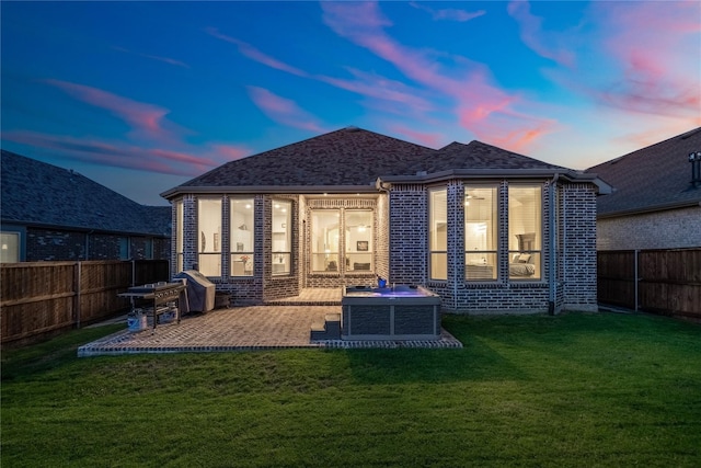 back house at dusk featuring a patio area, a yard, a jacuzzi, and central AC