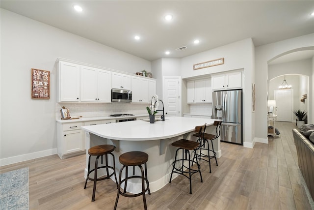 kitchen featuring backsplash, white cabinetry, an island with sink, and appliances with stainless steel finishes