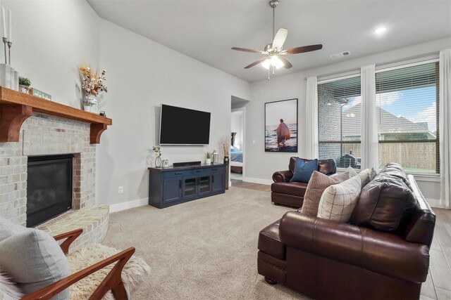 living room featuring ceiling fan, a fireplace, and light carpet