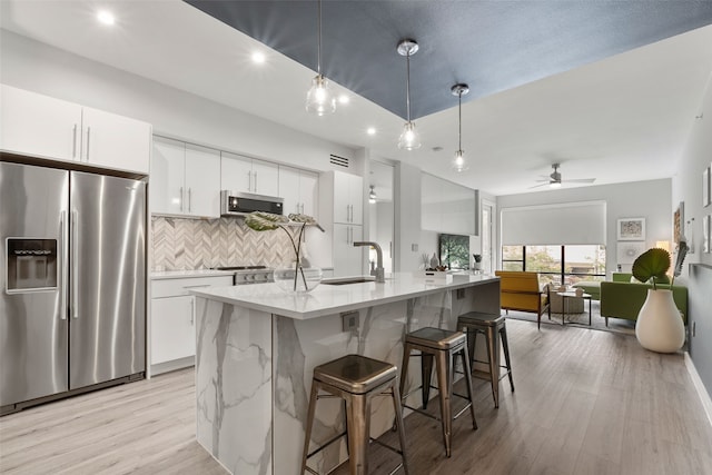 kitchen with appliances with stainless steel finishes, ceiling fan, sink, white cabinetry, and hanging light fixtures