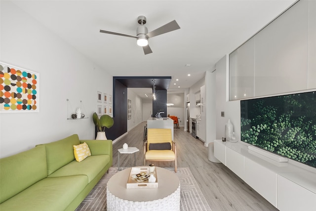 living room featuring light wood-type flooring, ceiling fan, and sink