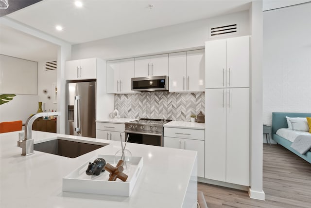 kitchen with tasteful backsplash, white cabinetry, sink, and appliances with stainless steel finishes