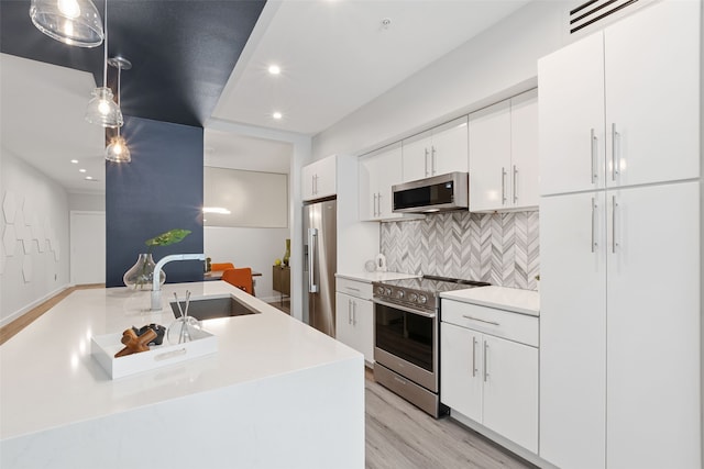 kitchen featuring sink, hanging light fixtures, stainless steel appliances, decorative backsplash, and white cabinets