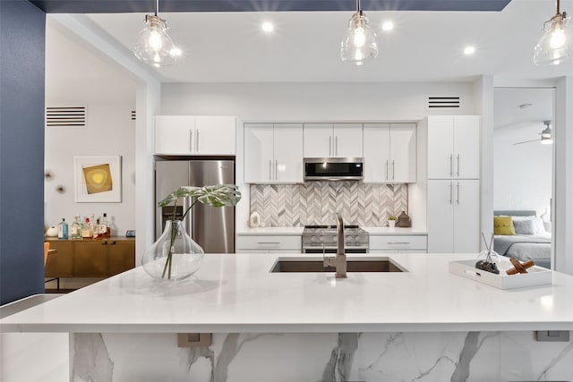 kitchen featuring backsplash, decorative light fixtures, a center island with sink, and stainless steel appliances