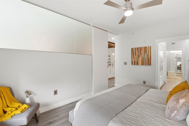 bedroom with ensuite bathroom, light hardwood / wood-style flooring, and ceiling fan