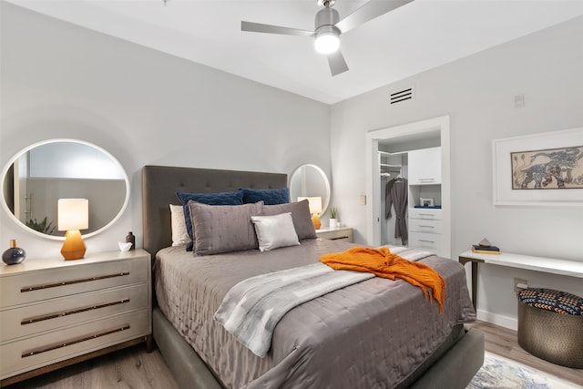 bedroom with a closet, a spacious closet, ceiling fan, and light hardwood / wood-style floors