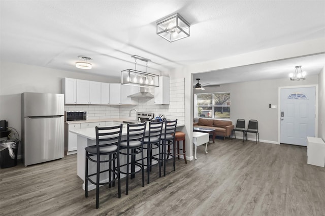 kitchen featuring white cabinets, appliances with stainless steel finishes, hanging light fixtures, and a breakfast bar area