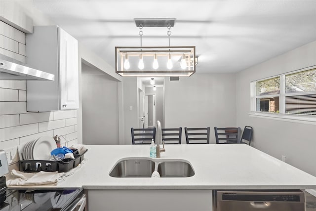 kitchen with sink, stainless steel dishwasher, decorative backsplash, decorative light fixtures, and range